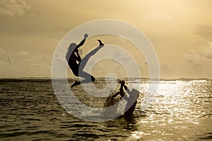 Silhouette of young woman jumping out of ocean