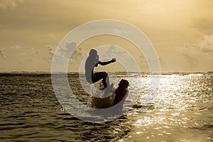 Silhouette of young woman jumping out of ocean