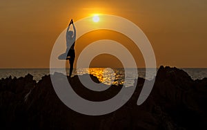 Silhouette young woman lifestyle exercising vital meditate and practicing yoga on the beach at sunset