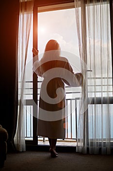 Silhouette of young woman looking out the window