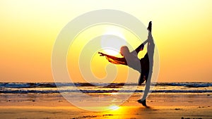 Silhouette of young woman performing rhythmic gymnastics element on the beach