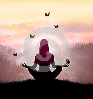 Silhouette of young woman practices yoga and meditates on top of the mountain with night sky, star and butterfly