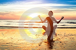 Silhouette young woman practicing yoga on the beach