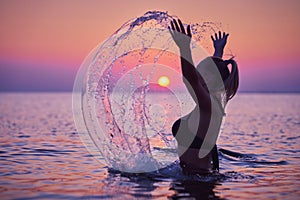 Silhouette of young woman practicing yoga on the beach at sunrise