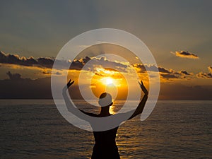 Silhouette young woman practicing yoga on the beach at sunset. Healthy live and active rest concept.