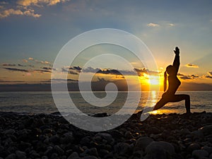 Silhouette young woman practicing yoga on the beach at sunset. Healthy live and active rest concept.