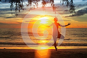 Silhouette young woman practicing yoga on the beach at sunset. Nature.