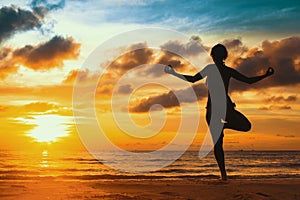 Silhouette young woman practicing yoga on the beach at sunset. Relax.