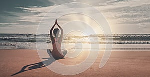 Silhouette young woman practicing yoga on the beach at sunset. Yoga and meditation on the calm peaceful beach at sunset. Fitness a