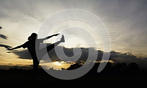 Silhouette of young woman practicing yoga outdoor. Female happiness. Sport and healthy concept