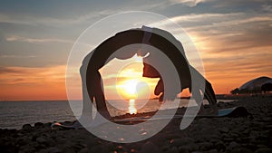 Silhouette young woman practicing yoga at sunset on the sea. Happy moments of life - silhouette yoga on the beach on the