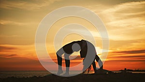 Silhouette young woman practicing yoga at sunset on the sea. Happy moments of life - silhouette yoga on the beach on the