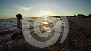 A silhouette of a young woman running along the beach to the sunset