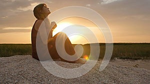 Silhouette of a young woman on the sand at sunset, girl praying to the god on horizon, the concept of vacations, religion, the bea