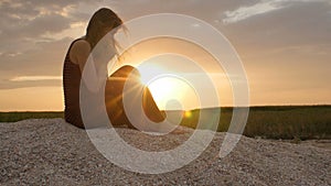 Silhouette of a young woman on the sand at sunset, girl praying to the God on horizon, the concept of vacations, religion, the bea