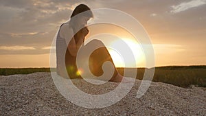 Silhouette of a young woman on the sand at sunset, girl praying to the God on horizon, the concept of vacations, religion, the bea