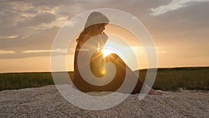 Silhouette of a young woman on the sand at sunset, girl praying to the god on horizon, the concept of vacations, religion, the bea