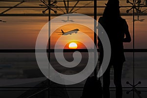 Silhouette of young woman is standing near window at the airport