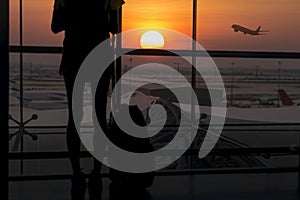 Silhouette of young woman is standing near window at the airport