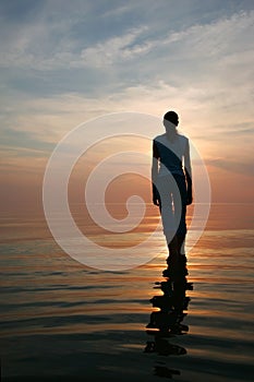 Silhouette of young woman standing in a water