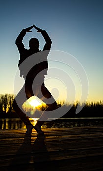 Silhouette of young woman at sunset doing yoga
