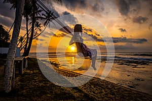 Silhouette of young Woman on a swing ,Beautiful sunset over the sea, ocean. Travel and vacation