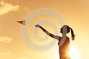 Silhouette of young woman throwing paper plane