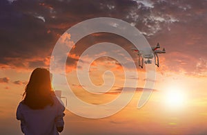 Silhouette of young woman using drone at sunset for photos and video making - Happy woman having fun with new technology trends in