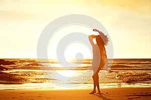 Silhouette young woman walking on beach during sunset