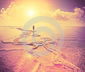 Silhouette of young woman walking on Dead Sea