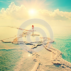 Silhouette of young woman walking on Dead Sea