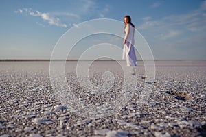 Silhouette of young woman walking on Dead Sea at sunrise. Solitude