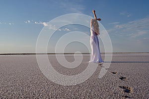 Silhouette of young woman walking on Dead Sea at sunrise. Solitude