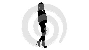 Silhouette Young woman walking with shopping bags talking on mobile phone.
