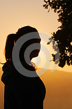 Silhouette of a young woman watching sunset