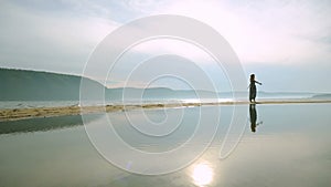 Silhouette of young women running around and jumping on the sandy beach at sunset.