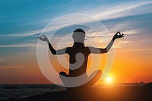 Silhouette of young yoga woman does meditation on sea beach