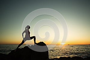 Silhouette of young yoga woman doing exercises on the ocean beach