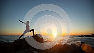 Silhouette young yoga woman doing fitness exercises on the sea beach