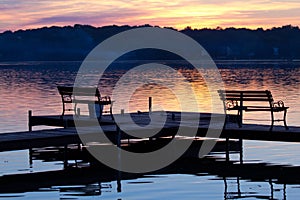 Silhouetted Benches on Wooden Pier at Sunset photo