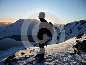 Silhouetted climber on snowy mountain summit