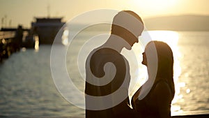Silhouetted couple hold each other and kiss on the beach. date on the seafront