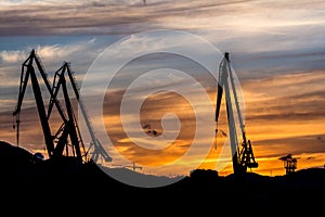 Silhouetted cranes at shipyard,
