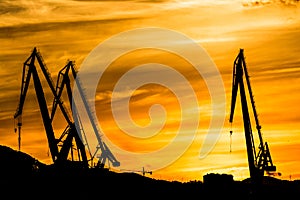 Silhouetted cranes at shipyard,