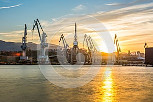 Silhouetted cranes at shipyard,