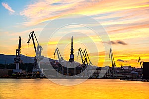 Silhouetted cranes at shipyard,