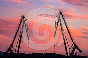 Silhouetted cranes at shipyard,