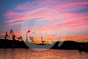 Silhouetted cranes at shipyard,
