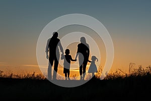 Silhouetted family holding hands at dusk