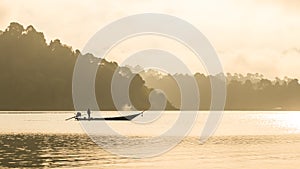 Silhouetted fisherman and boat with mountain background